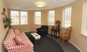 A room with a checkered sofa and a wooden chair.
