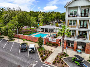 The Flats at Tioga Town Center apartments in Newberry, FL showing pool courtyard, brick facade and parking lot.