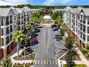 Shared courtyard and parking between four-story buildings at The Flats at Tioga Town Center apartments in Newberry, FL.