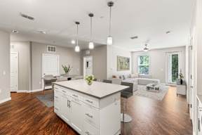 Open-concept kitchen and living area with island, pendant lights, and wood floors at apartments in Newberry, FL.