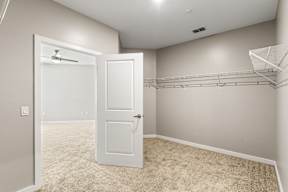 Walk-in closet with wire shelving and open door to carpeted bedroom at The Flats at Tioga Town Center.