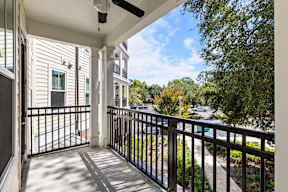 Covered balcony with black railing at The Flats at Tioga Town Center overlooking landscaped courtyard and parking.