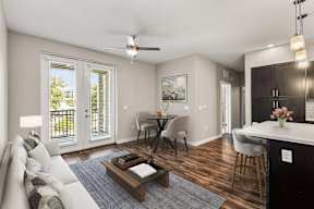 Living room with sofa, coffee table, dining nook, kitchen island and balcony doors in an apartment in Newberry, FL.