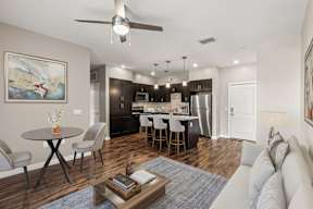 Open-plan living room and kitchen with island, dark cabinets and stainless appliances at The Flats at Tioga Town Center.