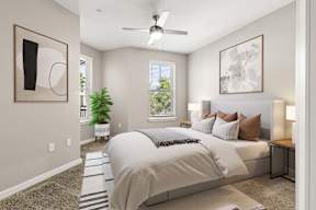 Bedroom at The Flats at Tioga Town Center with bed, bedside lamps, ceiling fan, and plant.