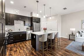 Modern kitchen and living area with island seating and stainless appliances at apartments in Newberry, FL.