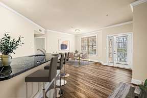 Modern kitchen with sleek black countertops, complemented by a dining area featuring a table and chairs at Claremont Apartments in Exton, PA