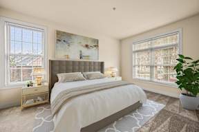 Inviting bedroom with a large bed, a framed painting, and a potted plant, creating a serene atmosphere at Claremont Apartments in Exton, PA