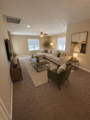 A living room with a white couch, a green armchair, and a television on the wall.