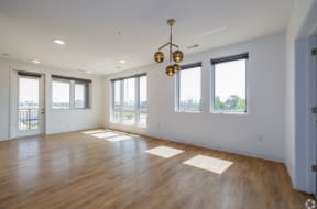 an empty living room with hardwood floors and a chandelier