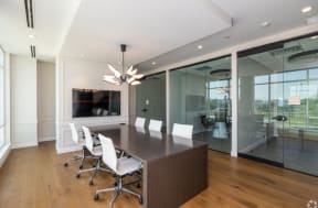 a large conference table with white chairs and a large tv on the wall