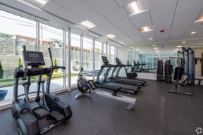 a photo of a gym with cardio equipment and windows