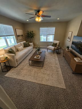A living room with a white couch, a coffee table, and a ceiling fan.