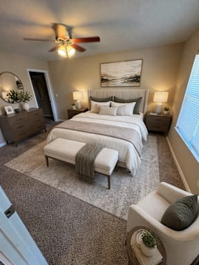 A bedroom with a large bed, a chair, and a painting on the wall.
