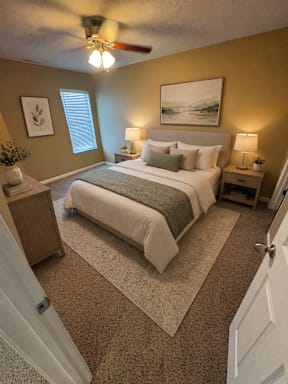 A bedroom with a bed, nightstands, and a ceiling fan.