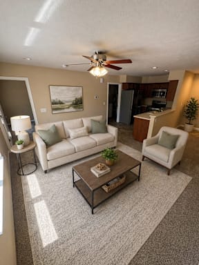 A living room with a white couch, a coffee table, and a ceiling fan.