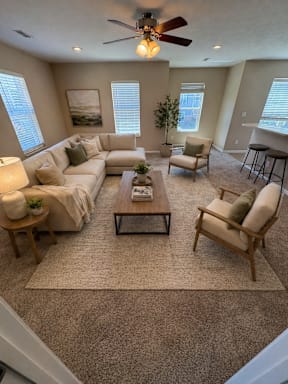 A living room with a beige sofa set, a coffee table, and a ceiling fan.