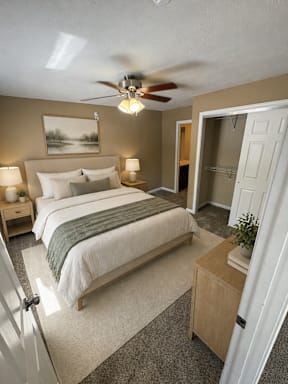 A bedroom with a bed, nightstands, and a ceiling fan.