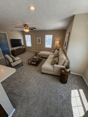 A living room with a grey carpet and a white sofa.