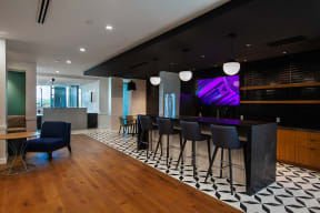 a bar area in the lobby of a building with black and white tiles and a purple screen