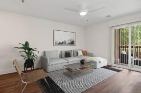 Model Living Room with Wood-Style Flooring and Patio Accessibility at Park at Caterina Apartments located in Charlotte, NC.