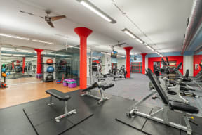 a gym with cardio equipment and weights on the floor and red pillars