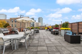 a rooftop patio with tables chairs and umbrellas and a city in the background
