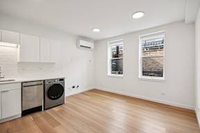 A clean, empty room with a washing machine and a window showing an outdoor view.