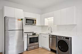 A kitchen with a stainless steel refrigerator, microwave, oven, and dishwasher.