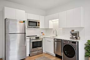 A modern kitchen with a stainless steel refrigerator, microwave, oven, dishwasher, and sink.
