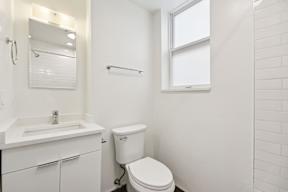 A white bathroom with a toilet, sink, and mirror.