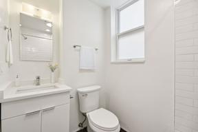 A white bathroom with a toilet, sink, and mirror.