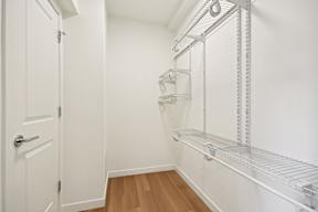 A white door is open to a hallway with a shelving unit on the wall.