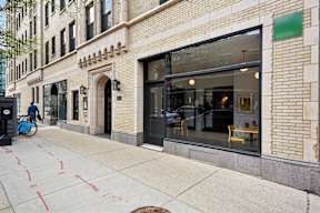 A street view of a building with a bicycle parked on the sidewalk.