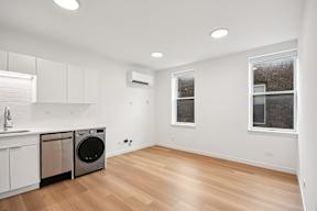 A clean, empty room with a washing machine and a window.
