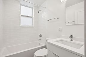 A white bathroom with a toilet, sink, and bathtub.