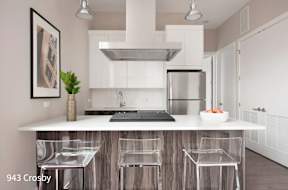 a white kitchen with a bar and a stainless steel refrigerator