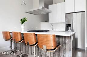 a kitchen with a white counter top and wooden bar stools