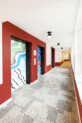 a hallway with red walls and a patterned carpet and red doors