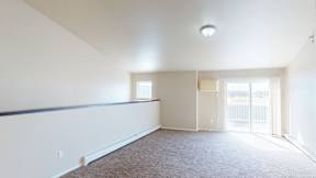 A large, empty room with a carpeted floor and a window.