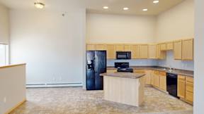 A kitchen with a black refrigerator, wooden countertops, and a microwave.