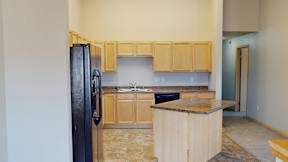 A kitchen with wooden cabinets and a black refrigerator.