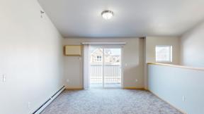 A spacious empty room with a sliding glass door leading to a balcony.