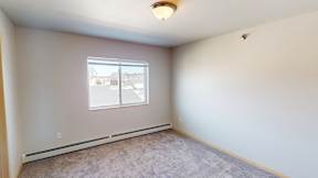 A room with a window and a carpeted floor.