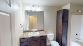 A bathroom with a sink, toilet, and a mirror.