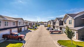 A row of houses with cars parked in front.