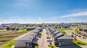 A long row of houses with cars parked in front.