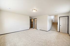 A spacious room with a staircase and a door.
