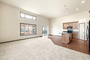 A spacious living room with a kitchen area in the background.