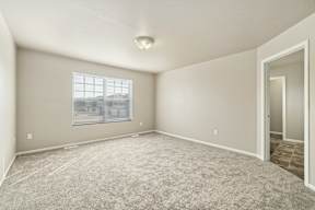 Empty room with a window and carpeted floor.